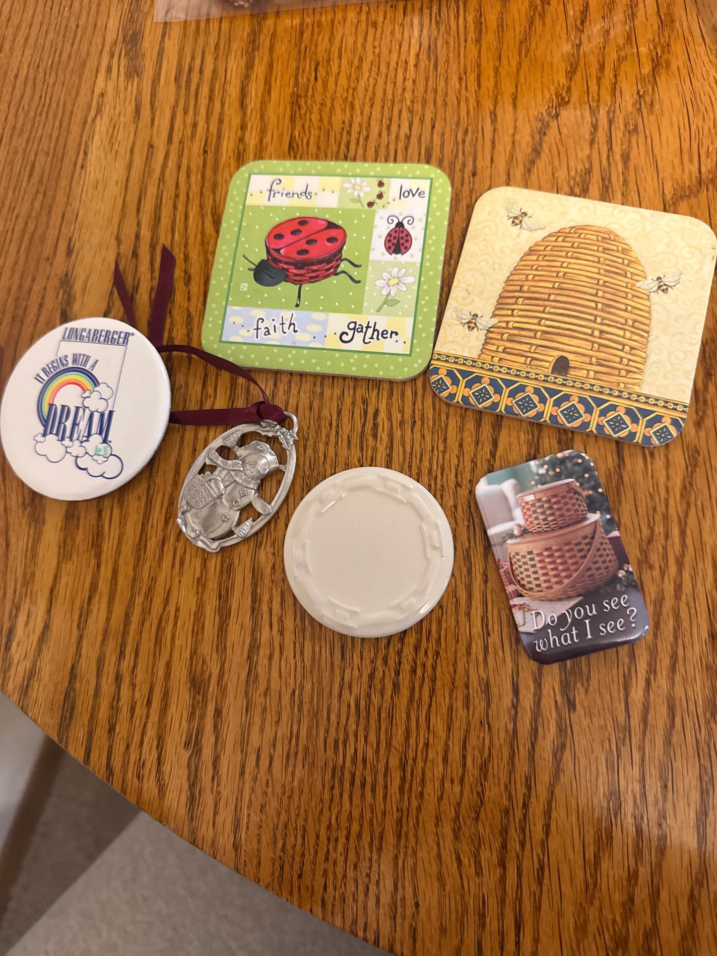 Longaberger items sold as a lot (pewter ornament, ivory pottery chip, 2 coasters, and various pins)